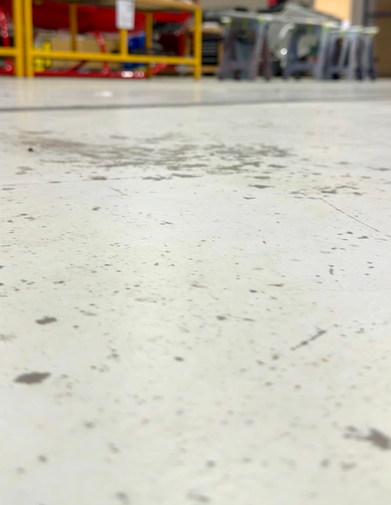 Worn and dirty concrete hangar floor at a commercial facility prior to surface preparation and coating installation in Boulder City, Nevada.
