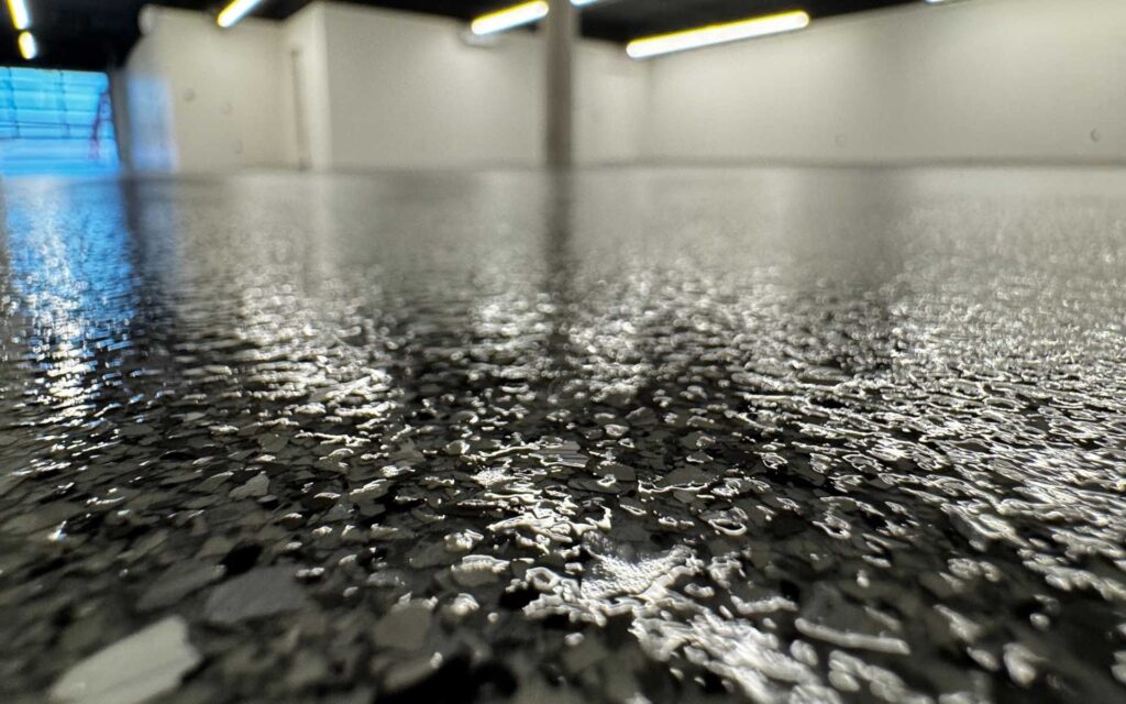 Close-up of slate gray hybrid flake garage floor coating with double topcoat installed in an extra-large residential garage in Las Vegas